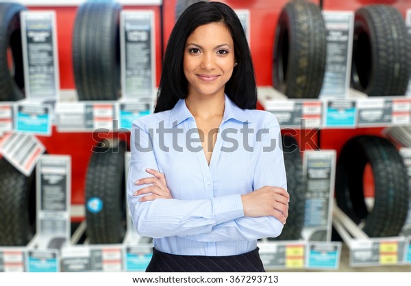 Auto dealer woman near a\
car tire.