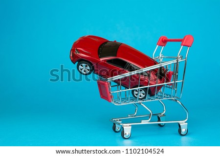 auto dealership and rental car concept.  red car shopping cart blue background