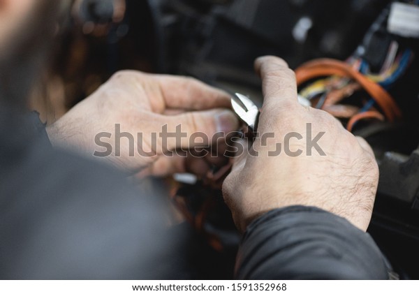 Auto\
electrician is working with car wiring close\
up.