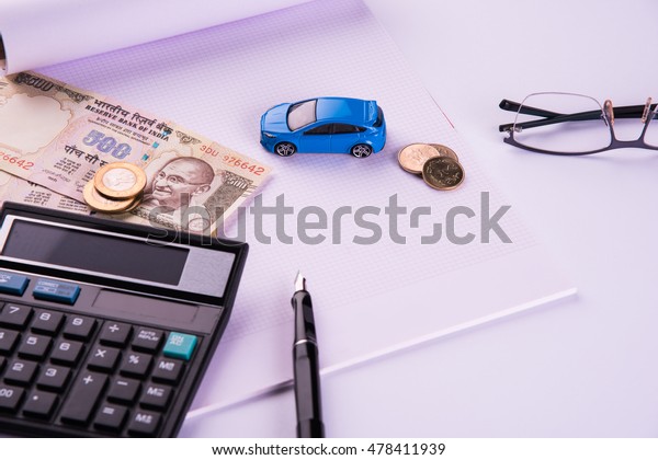 Auto Finance/ Loan in\
India -  Concept showing toy Car model, keys, indian currency notes\
and calculator for EMI calculations etc arranged over clear\
background