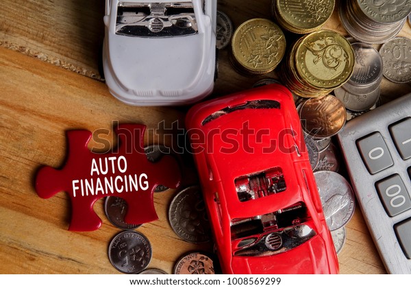 AUTO FINANCING CONCEPT : Small\
cars,coins,piece of puzzle and calculator on wooden table.\
