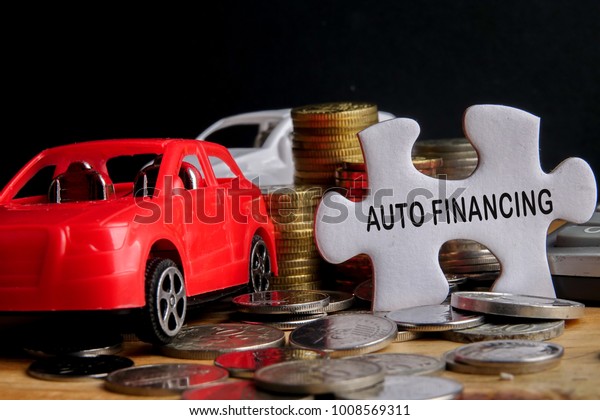 AUTO FINANCING CONCEPT : Small\
cars,coins,piece of puzzle and calculator on wooden table.\
