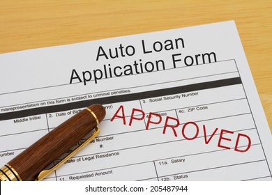 Auto Loan Application Form With Approved Stamp And A Pen On A Wooden Desk