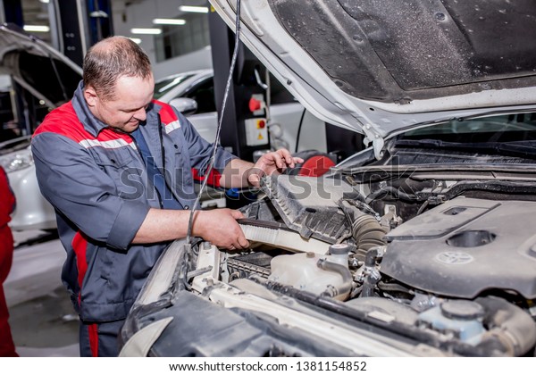 Auto maintenance. The car repairman changes the\
oil, checks the wheels, changes parts, performs maintenance. Modern\
universal car center.