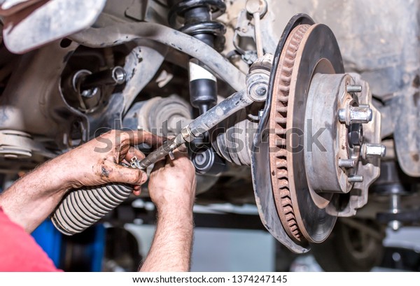Auto\
maintenance. Repair of brake system on car wheels. The car\
repairman changes the oil, checks the wheels, changes parts,\
performs maintenance. Modern universal car\
center.