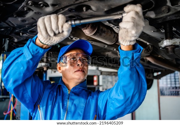 Auto mature mechanic repairman in uniform using\
a socket wrench working auto suspension repair in the garage,\
change spare part, check the mileage of the car, checking and\
maintenance service\
concept.