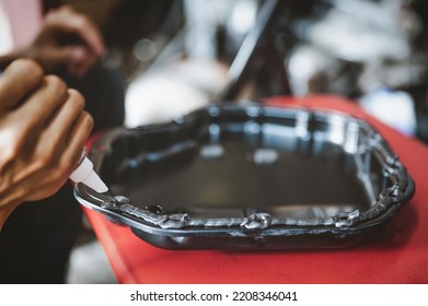 Auto Mechanic Applying Black High-temp RTV Silicone Gasket Maker To Oil Pan Flange.