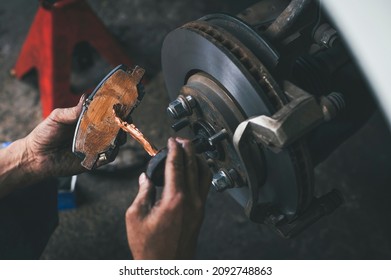 Auto mechanic applying a high temp brake grease on the brake pads. - Shutterstock ID 2092748863