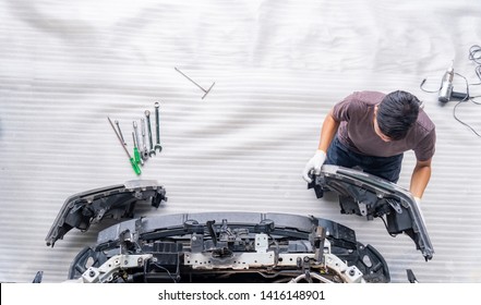 Auto Mechanic Is Assembling Car Parts, Mechanic Changing Car Headlight In A Workshop ,white Background ,Top View