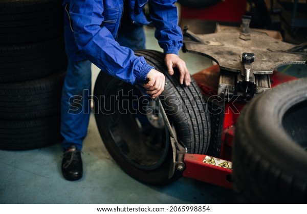 Auto mechanic balances the car wheel on the\
wheel balancer