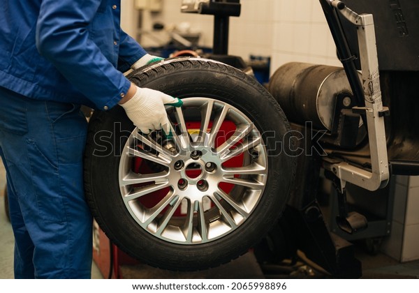 Auto mechanic balances the car wheel on the\
wheel balancer
