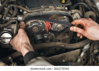 Auto mechanic changes the timing belt in the car, close-up
