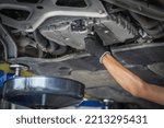Auto mechanic changing engine oil.