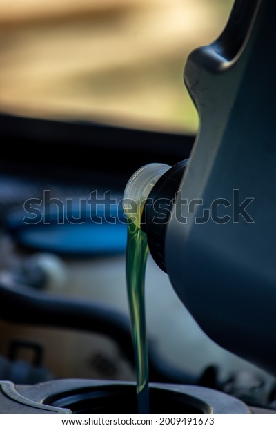 An auto mechanic changing oil pours oil into a car\
engine. Selective focus