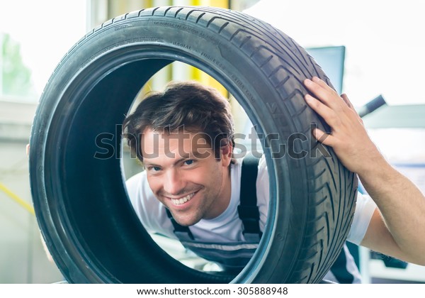 Auto mechanic\
changing tire in car\
workshop