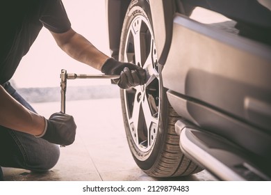 Auto mechanic checking air pressure and inflating car tires. Concept of car care service and maintenance.