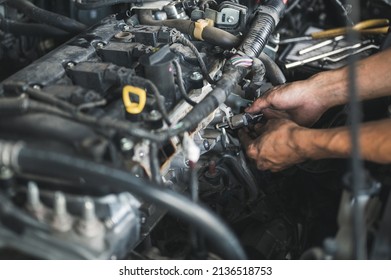 Auto Mechanic Checking Bad Fuel Injector From The Engine.