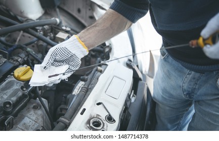 Auto mechanic checking the car engine oil level.