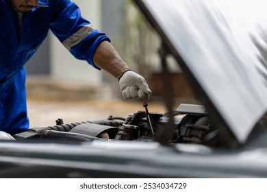 Auto mechanic checking engine and engine oil.