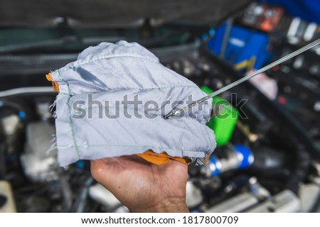 Auto mechanic checking engine oil level.