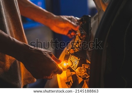 Auto mechanic checking rear turn signal bulbs.