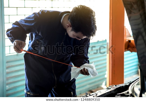 Auto mechanic checks the oil in a car\
garage to make car care. Concept Service by\
car.