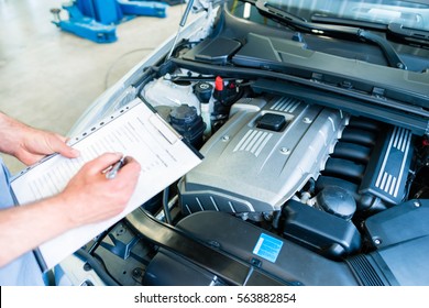 Auto Mechanic Controlling  Car With Checklist In Workshop 