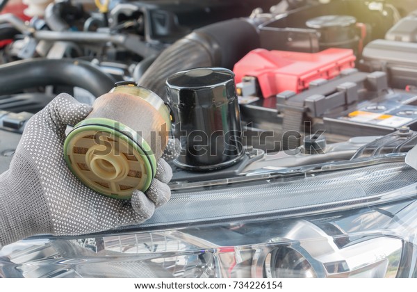 Auto mechanic with dirty hands and oil\
filter. Service\
maintenance.
