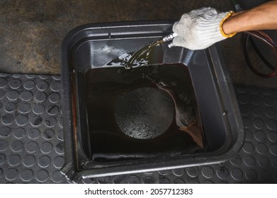 Auto Mechanic Draining Old Used Automatic Transmission Fluid Into The Oil Drain Pan.