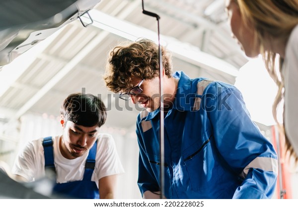 Auto Mechanic explaining and showing\
the point at vehicle part for repair to Asian woman customer at\
garage shop, Car service and maintenance\
Concept