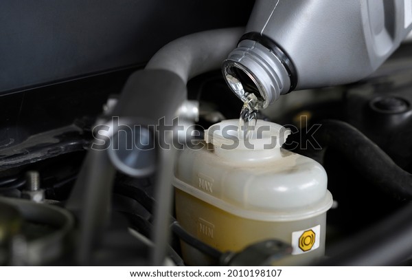 Auto mechanic filling brake fluid in brake\
fluid reservoir.
