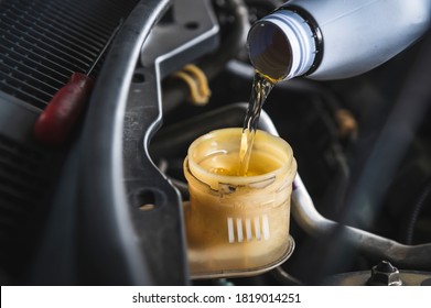 Auto mechanic filling DOT 4 brake fluid in brake fluid reservoir. - Shutterstock ID 1819014251