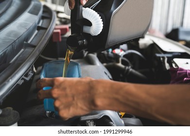 Auto mechanic filling a new synthetic motor oil into the engine. - Shutterstock ID 1991299946