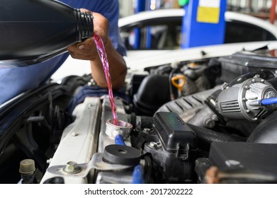 Auto Mechanic Filling Pre-mixed Long Life Coolant Fluid In Aluminum Car Radiator Fill Hole.