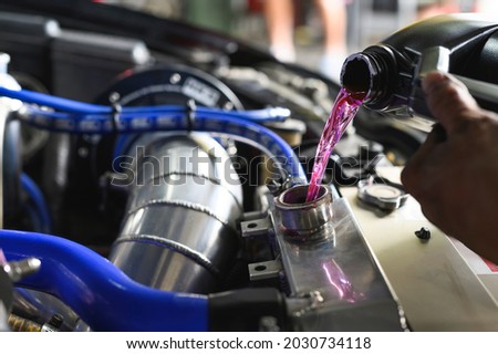 Auto mechanic filling Pre-mixed Super Long Life Coolant fluid in aluminum car radiator fill hole.
