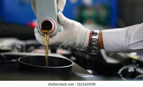 Auto mechanic in gloves pour engine oil into engine - Shutterstock ID 2121623558