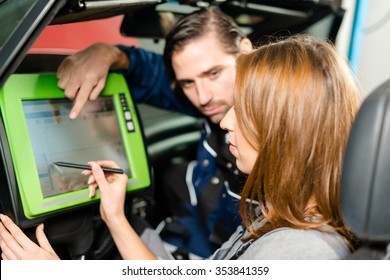 Auto mechanic is guiding a female trainee in checking the car performance with a digital device. Concept for the fact that more and more women participate in jobs previously typical for men.  - Powered by Shutterstock