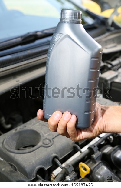 Auto mechanic hand\
holding motor oil 