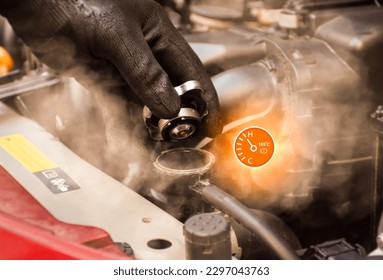 Auto mechanic hand opens the radiator cap with steam escaping around the engine compartment from the high heat,water temp gauge symbol with high temperature,Car maintenance service concept. - Shutterstock ID 2297043763