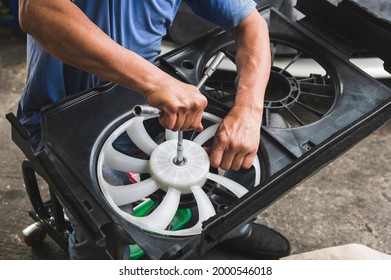 Auto Mechanic Hands Installing A Radiator Cooling Fan Into Radiator Fan Housing.