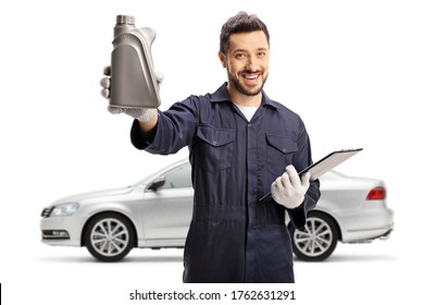 Auto mechanic holding a bottle of engine oil and posing with a silver car isolated on white background