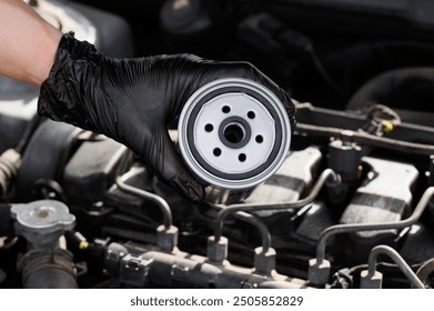 Auto mechanic holding fuel filter for diesel cars against background of engine compartment of car, close-up. Auto parts replacement, car maintenance. Checking filter condition before installation.  - Powered by Shutterstock