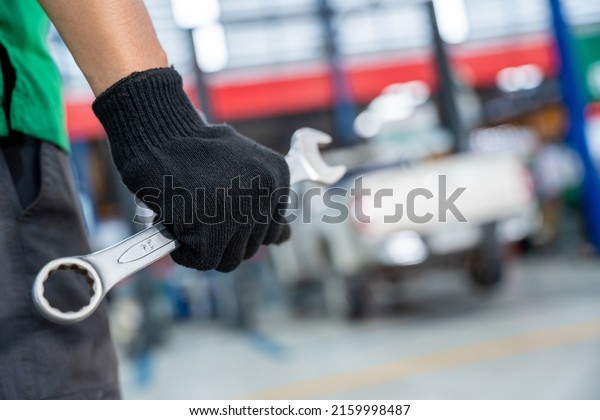Auto Mechanic holding a wrench in Car repair\
service center.