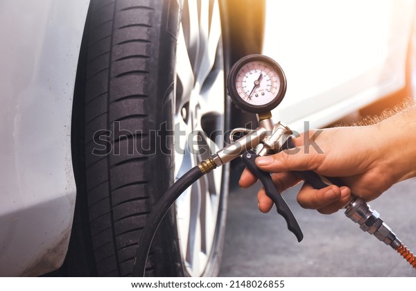 A auto mechanic inflates a tire with an air tire\
inflating gun