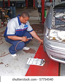 Auto mechanic inspecting a carâ??s tire pressure in a service garage.