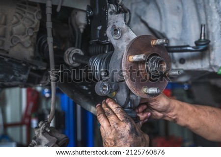 Auto mechanic installing car suspension.