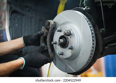 Auto mechanic installing front brake calipers and brake pads.