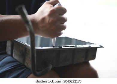 Auto Mechanic Installing An RTV Silicone Liquid Gasket On The Oil Pan Flange.