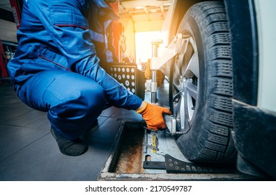 Auto mechanic installing sensor during suspension adjustment and automobile wheel alignment work at repair service station. Close up - Shutterstock ID 2170549787