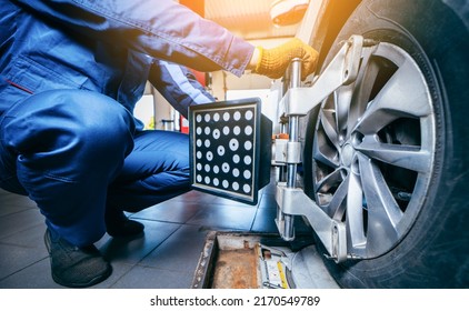 Auto mechanic installing sensor during suspension adjustment and automobile wheel alignment work at repair service station. Close up
